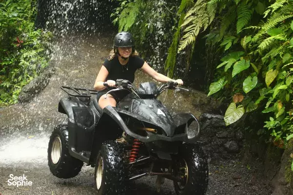 Helmeted rider on a quad bike splashing through a narrow jungle track with Gordo Bali Tour near Ubud
