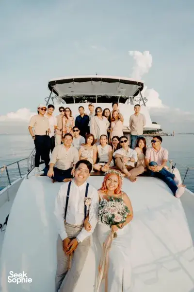 Group posing on the deck of a 57ft yacht in Singapore with open sea and clouds behind them on a Lazarus Island outing