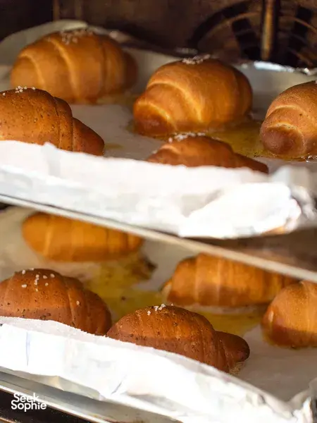 Golden shio pan buns cooling on lined trays on wooden racks inside the bakery for hands-on workshops in Singapore