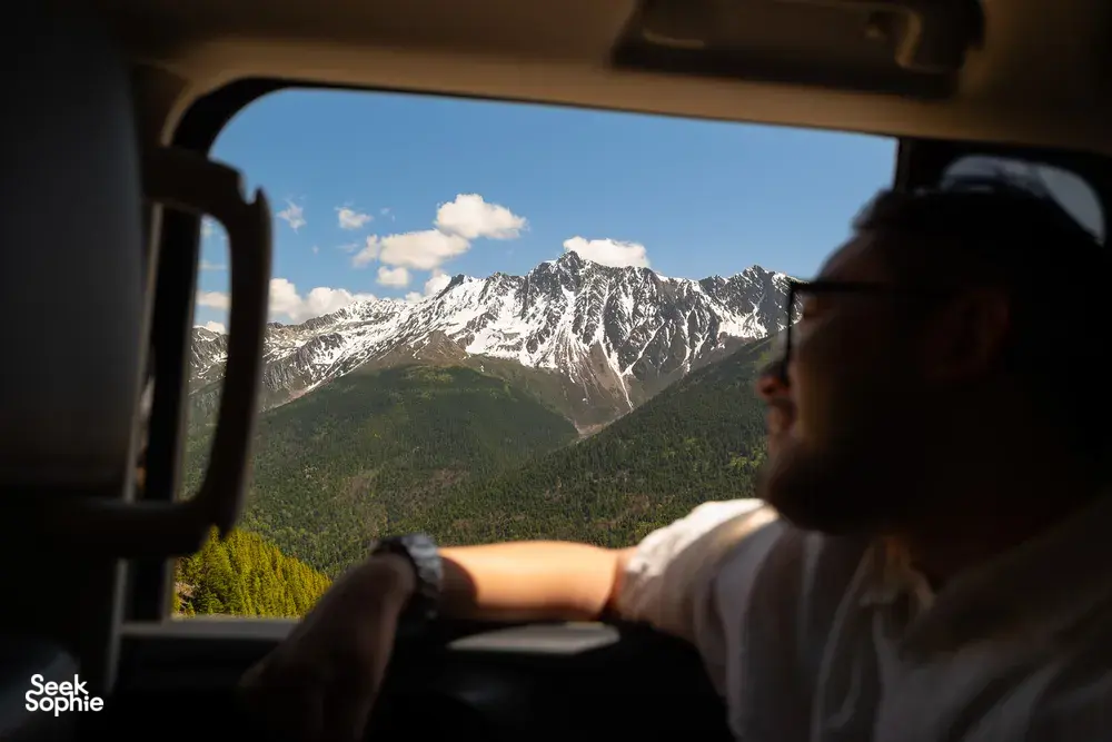 Traveller gazing from a vehicle window at snow-capped peaks near Shangri-La during a 6-day Loop with a Tibetan guide