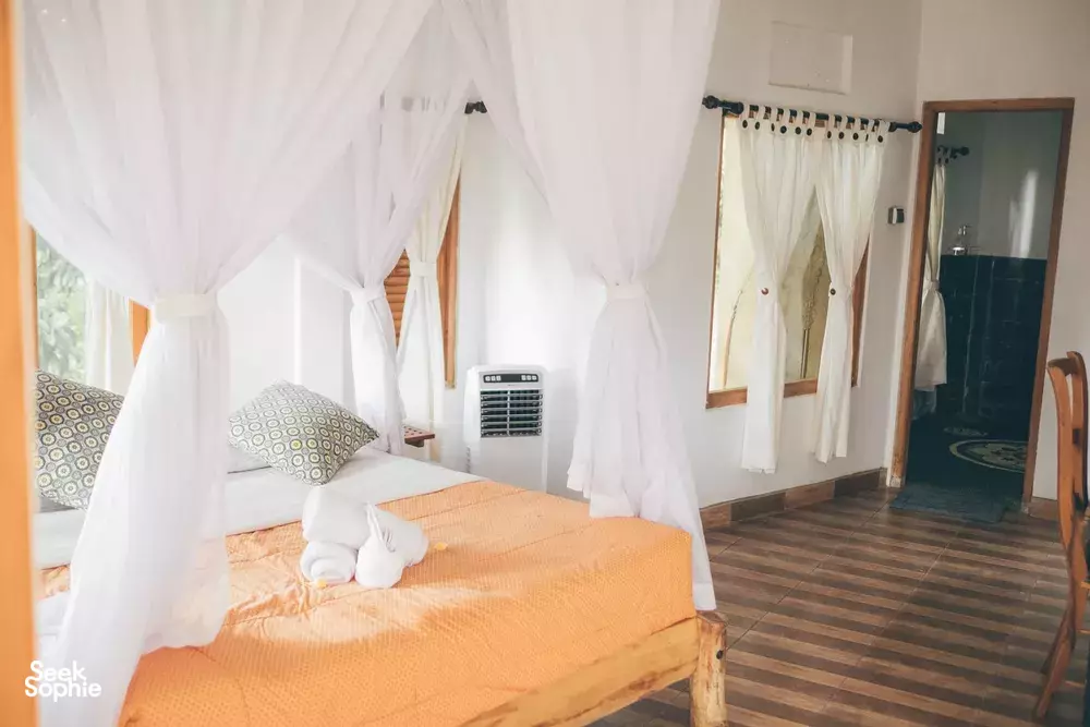 White-canopy bed in a bright guest room at Omunity Bali in Bali, part of a 3D2N sacred retreat