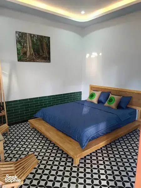 Quiet bedroom interior for a private 3D2N Cat Tien ethical tour, with a double bed and forest wall art by Next Continent