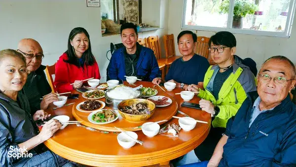 Communal lunch at a round table with bowls and chopsticks indoors during a countryside trek with The Bivou Lijiang in Lijiang