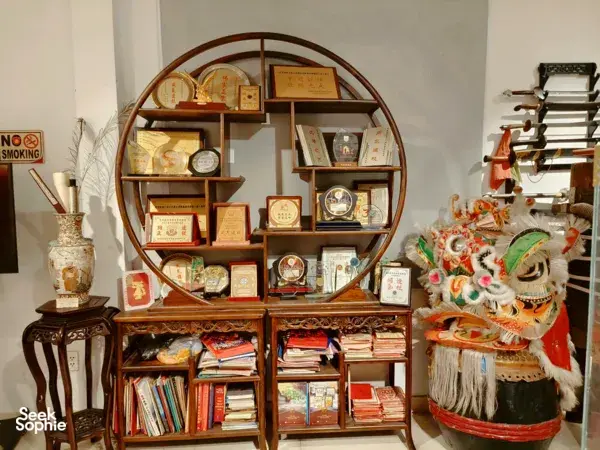 Lion dance costume head and wooden shelves of training manuals and memorabilia inside a kung fu museum in Ho Chi Minh City