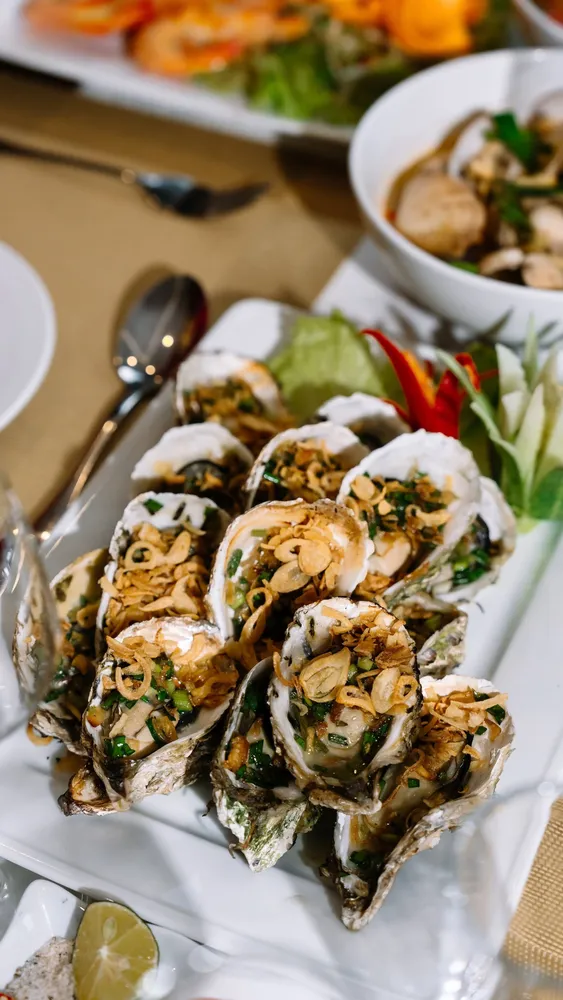 Seafood appetisers on white plates at a private dining table inside a Cat Ba luxury cruise cabin by Sunshine Golden Cruises