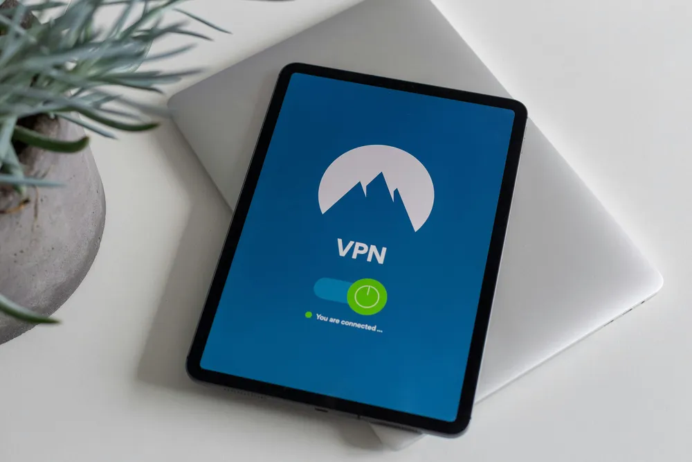 Tablet showing a VPN connection screen on a desk, with a potted plant nearby in a quiet workspace setting