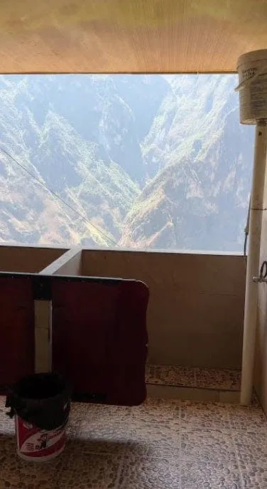 Terrace interior looking out onto a steep mountain valley with misty ridges, seen from a small furnished guest room veranda