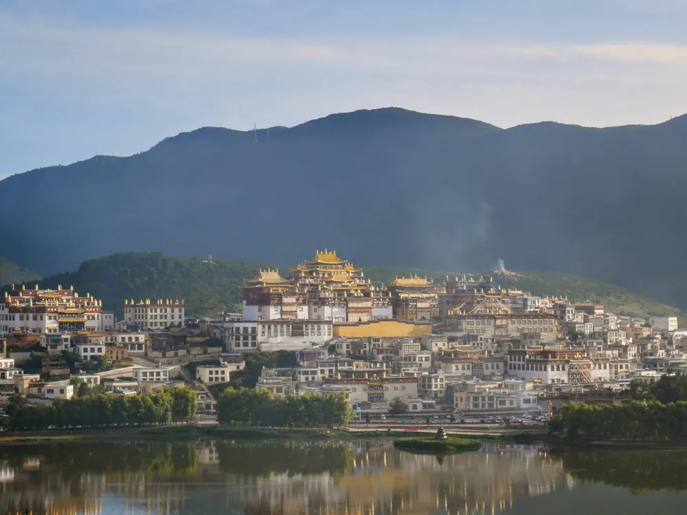Golden temple complex on a hillside overlooking water.