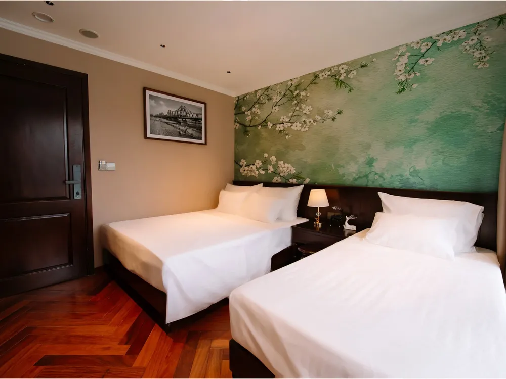 Twin beds in a luxe cabin on a 2D1N Cat Ba cruise with Sunshine Golden Cruises, floral mural feature wall