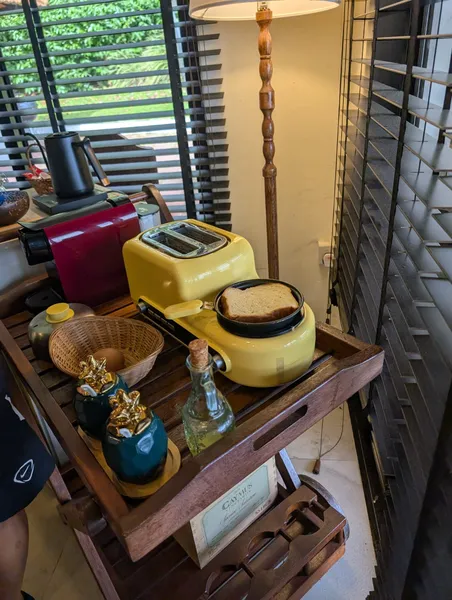 Breakfast setup with a yellow toaster, coffee pot and bread on a wooden table inside a Singapore farmstay by the sea