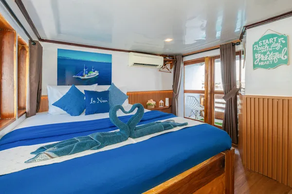 Blue-and-white cabin bed on a wooden Komodo boat trip, folded towel decoration on the 3D2N stay in Labuan Bajo