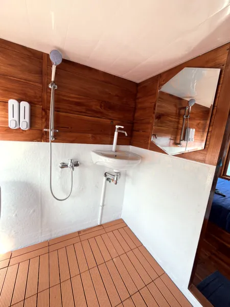 Onboard bathroom on La Famille’s wooden phinisi, with shower fittings and basin for a 3D2N shared Komodo cruise to Komodo Island