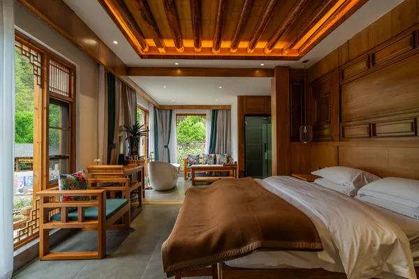 Cozy Shangri-La bedroom with neatly made beds, wooden chairs by the window and a warm, timber ceiling inside