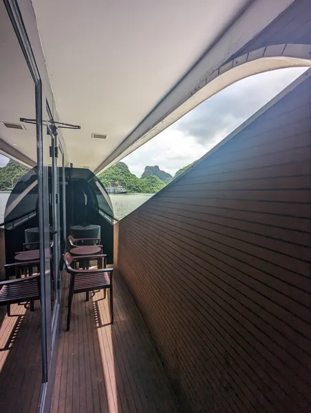 Open-air deck terrace with lounge chairs on the Oasis Bay Party Cruiser, with limestone karst views on Halong Bay