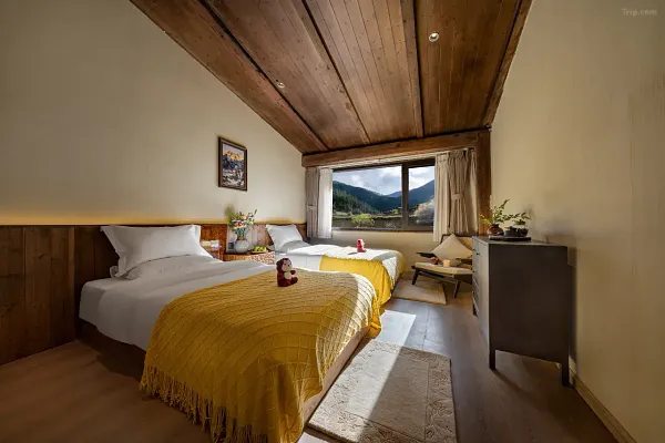 Rustic bedroom in Shangri-La with a vaulted wooden ceiling, twin beds with soft cushions, and a window framing distant mountains