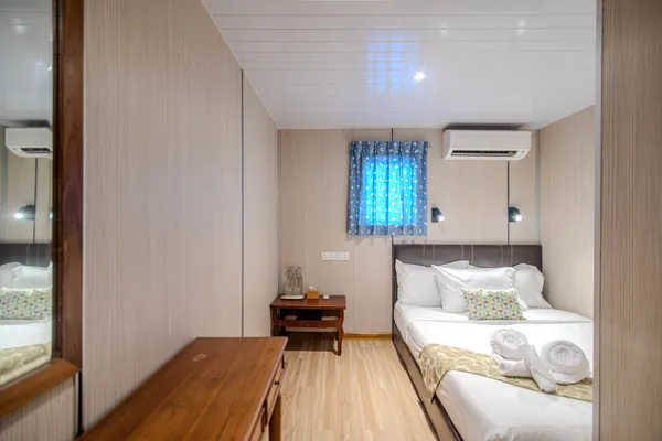 Seaventures Dive Rig suite interior with a double bed, stacked towels and pillows, blue light feature and wood storage bench