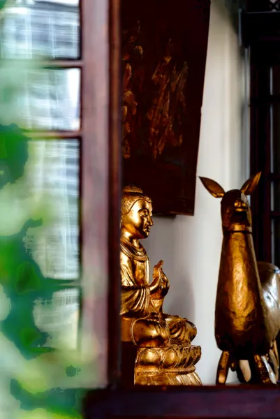 Patung penjaga berwarna emas dan hiasan rusa di bilik halaman Linden Centre heritage stay, Pekan Lama Xizhou, Dali