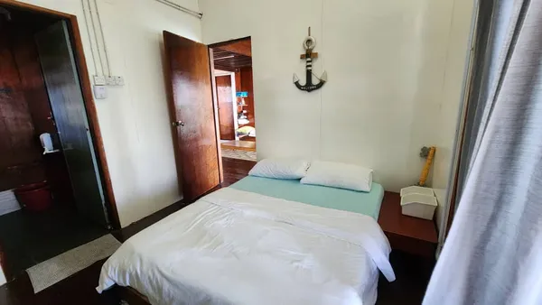 Bed in a simple room at Luma Selakan sea lodge in Semporna for a 2D1N dive and stay, with open door and wall hooks