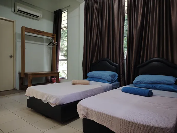 Two single beds in a tiled room with brown curtains and an air-conditioning unit, part of the 3D2N Deramakot Safari in Sandakan
