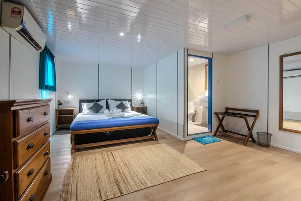 Tidily made double bed with blue runner and glass door to the bathroom on Seaventures Dive Rig offshore rig stay, Semporna