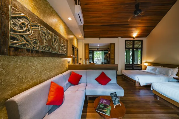 Borneo Rainforest Lodge suite lounge with sofa and twin cushions, open plan bedroom beyond, in Danum Valley