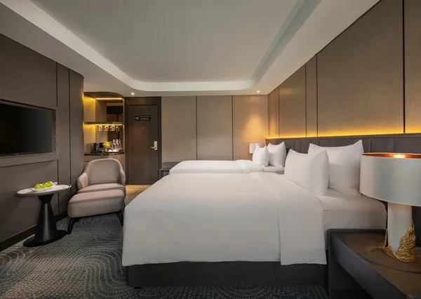 Kabin modern di Tulip Cruise dengan sofa, layar TV besar, dan dua tempat tidur single dalam pencahayaan hangat, di Teluk Halong