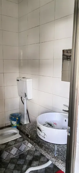 Compact tiled bathroom in Xishuangbanna tea lodge, with a toilet, sink basin, and bathtub in a small granite-finished corner