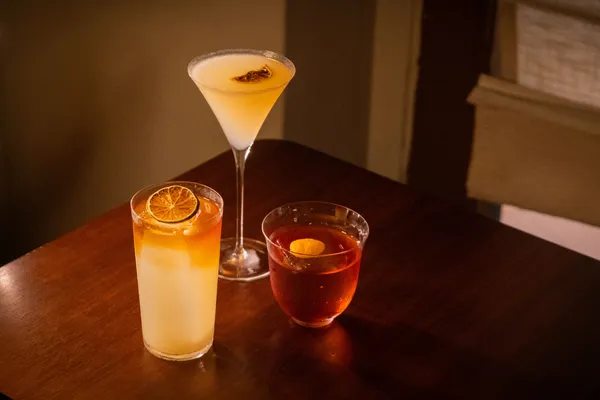 Tiga koktail racikan di bar koktail yang intim di Singapura, tersaji di atas meja kayu dan siap dicicipi dalam pengalaman private dining di Singapura