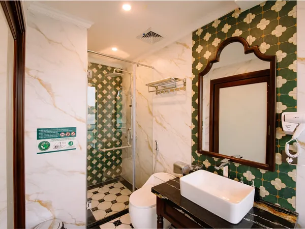 Marble bathroom on a Cat Ba cruise by Sunshine Golden Cruises, with private tub, glass shower and vanity mirror in floral-patterned walls