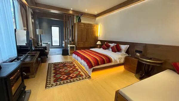 Cozy bedroom in Shangri-La with a red-and-cream striped duvet, patterned rug, bedside tables, and a balcony-facing window