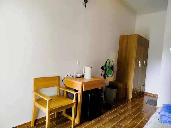 Green Hope Lodge room desk with kettle and small appliances beside a chair, tiled floor and bright window at Cat Tien