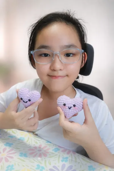 Participant holding two purple crocheted heart plush toys during an art-jamming self-expression session, one of workshops in Singapore