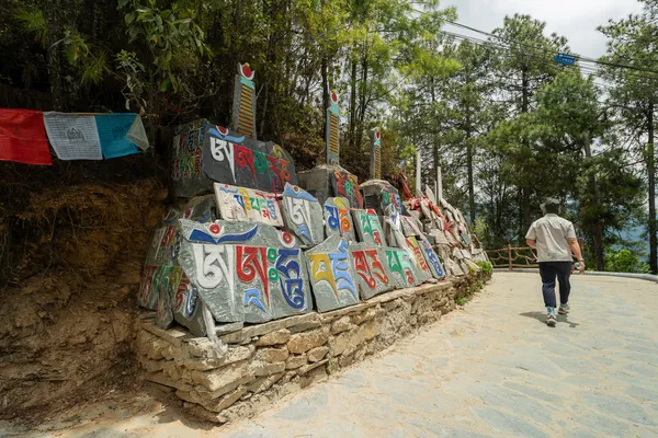 Tibetan prayer flags along a roadside stupa wall as a hiker walks on the Shangri-La loop during a 6-day trek with a guide