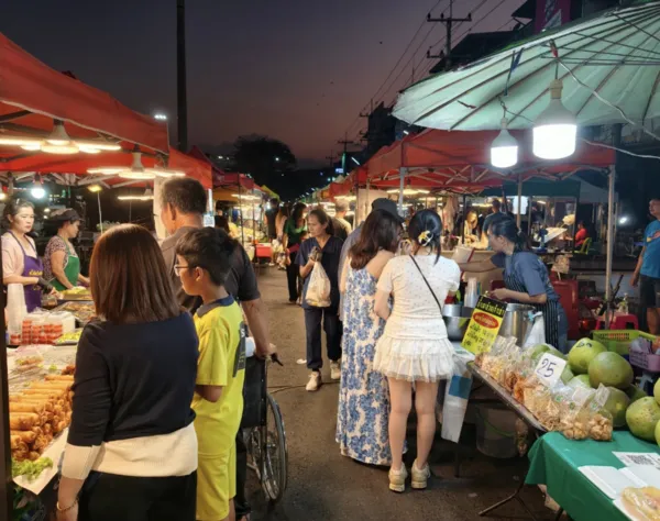 Travellers browsing stalls at a night market during a Khao Yai wildlife day trip, with fruit and snacks on display