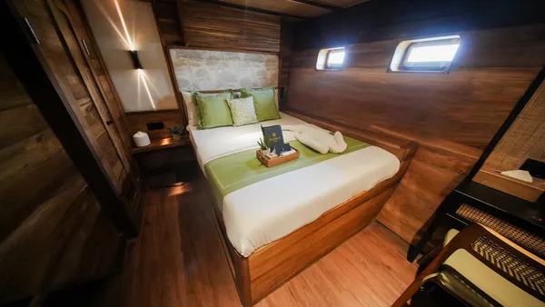 Modern luxe phinisi cabin with neatly made bed and green accents for the 3D2N Komodo cruise, in-cabin comfort in Labuan Bajo