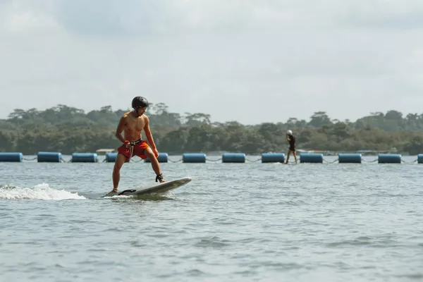 Paddleboarder gliding on a wide lake near moored boats as another paddler moves in the distance under soft daylight
