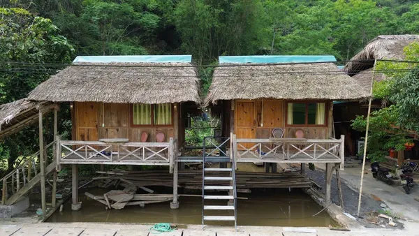 Ha Giang Expeditions camping cabins on stilts in Ha Giang, with thatched roofs and outdoor beds for the 3D3N Ha Giang Loop