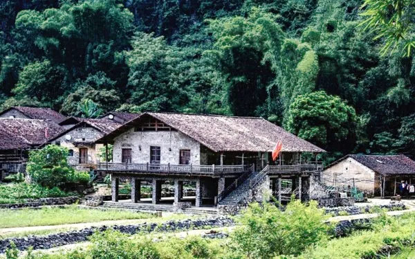 Traditional stilt houses with tiled roofs in a lush Cao Bang valley, part of a China–Vietnam borderland motorbike loop