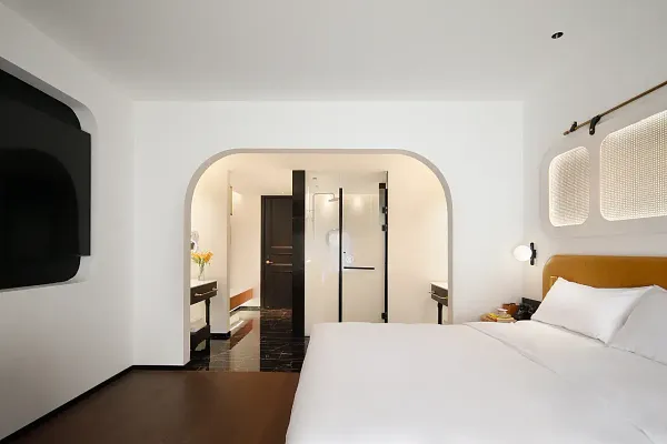 Bed in The Bivou Lijiang boutique room at Shuhe Ancient Town, with arched doorway and wall-mounted TV