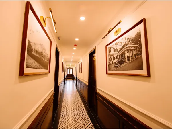 Wood-panelled corridor on a Cat Ba cruise by Sunshine Golden Cruises, lined with framed photos and patterned carpet lighting