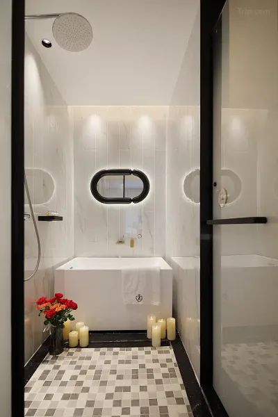 Minimalist en-suite bathroom with white tiles, bathtub, and warm candles at The Bivou Lijiang in Shuhe Ancient Town