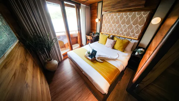 Angelica Liveaboard cabin on a 3D2N luxe Komodo cruise with a sunny window, patterned wall and made-up bed, Komodo Island