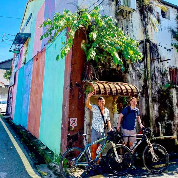Cyclists arriving on bikes by a sunny artsy doorway on a street in Kuching during a jungle cycling adventure