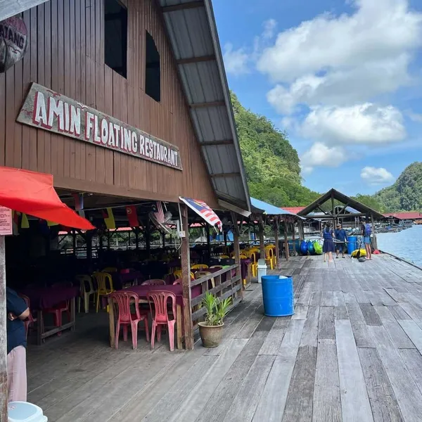 Wooden jetty dining at a floating restaurant on the water in Langkawi, set up for travellers after a mangrove cruise