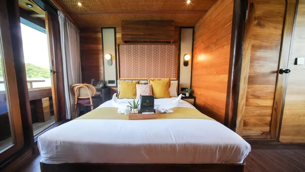 Angelica Liveaboard cabin on a 3D2N luxe Komodo cruise with a central double bed, bedside lamp and chair, in Komodo Island