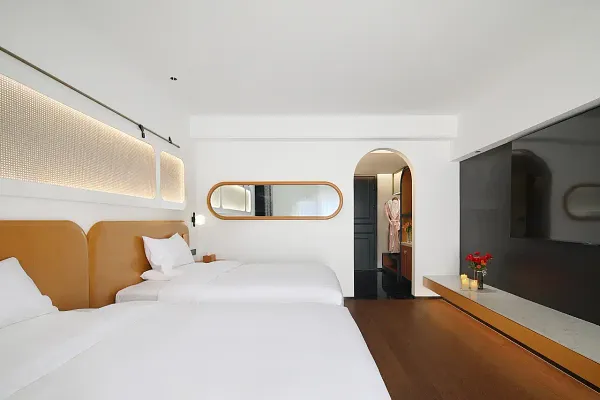 Minimal double bedroom at The Bivou Lijiang in Shuhe Ancient Town, with twin beds, oval mirror and dark sideboard