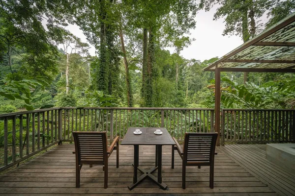 Rainforest-view wooden outdoor private deck with dining table and chairs at Borneo Rainforest Lodge, Danum Valley
