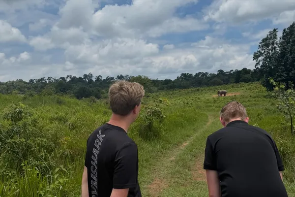 Two travellers walking along a grassy track in Khao Yai National Park during a guided wildlife safari trek