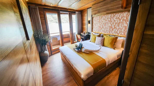 Angelica Liveaboard room on a 3D2N luxe Komodo cruise with balcony doors, a double bed and an orange patterned headboard, Komodo Island