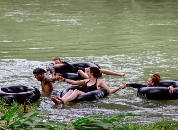 Inner-tube floaters paddling through green water near Cheow Lan Lake on a family rafthouse stay in Khao Sok National Park